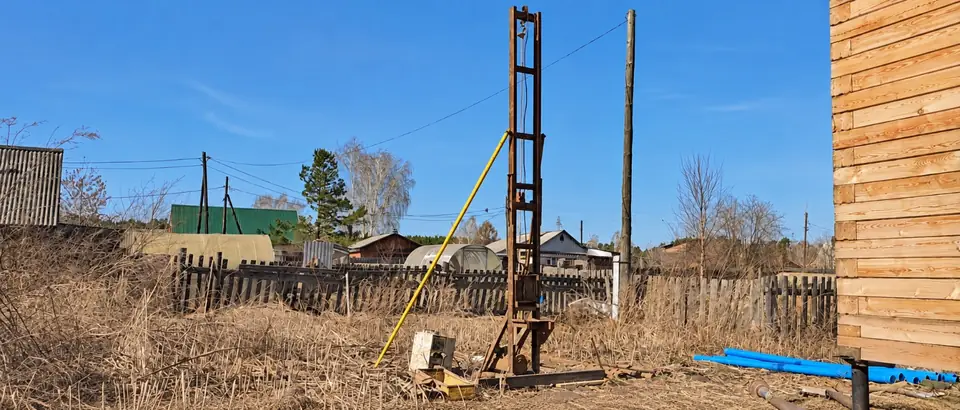 Малогабаритная буровая установка рядом с деревянным домом в Кузовлево